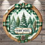 A round wooden frame with a winter scene of pine trees and a sign that says "Warm Wishes" in the center.