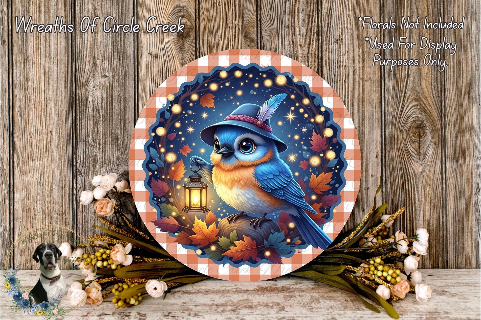 A decorative plate featuring a blue bird wearing a hat and holding a lantern, surrounded by autumn leaves and flowers, with a wooden background.