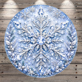 A large, ornate snowflake design with intricate details and sparkling crystal elements, set against a wooden background.
