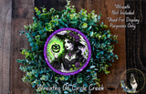 a wreath with a woman wearing a witch's hat and holding a pumpkin, surrounded by green foliage.
