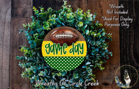 a wreath made of green and yellow leaves, with a football prominently displayed in the center. The wreath is set against a wooden background, and there is a text overlay that reads "Game day" and "Wreaths of Circle Creek".