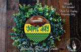 a wreath made of green and yellow leaves, with a football prominently displayed in the center. The wreath is set against a wooden background, and there is a text overlay that reads "Game day" and "Wreaths of Circle Creek".