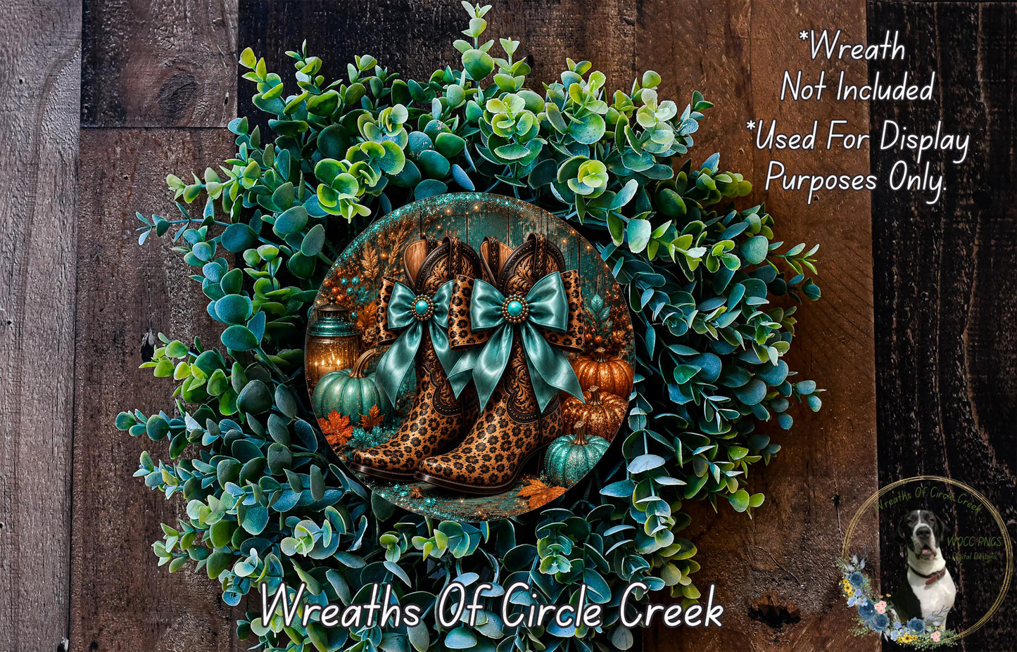 a wreath made of various materials, including green leaves, pumpkins, and leopard print boots. The wreath is displayed on a wooden surface, and there is a small dog in the background.
