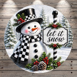 A snowman wearing a black and white top hat and scarf, with a sign that says "let it snow", surrounded by pine trees and holiday decorations.