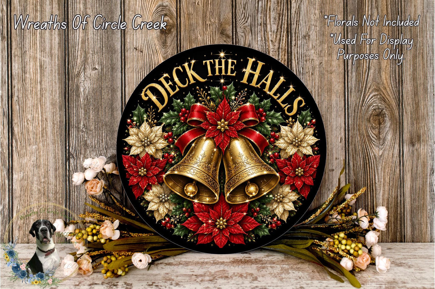 A decorative wreath with the text "Deck the Halls" and bells, surrounded by red poinsettias and greenery, placed on a wooden surface.