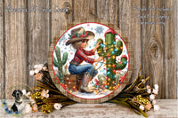 A decorative round wall hanging featuring a woman in a cowboy hat sitting next to a cactus, surrounded by flowers and holiday lights.
