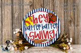 a round sign with the text "Hey patter batter swing" and a baseball graphic, surrounded by a wreath of flowers and a wooden background.