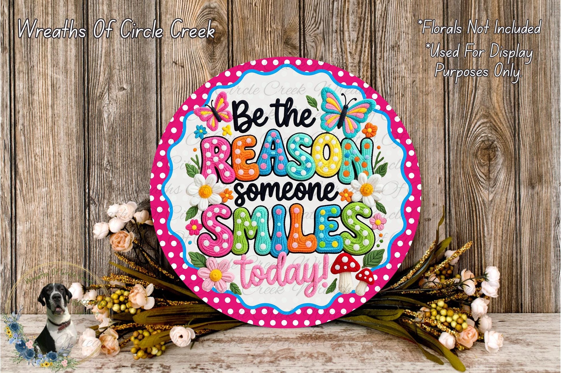 A colorful sign with the text "Be the reason someone smiles today!" surrounded by flowers and a wooden background.