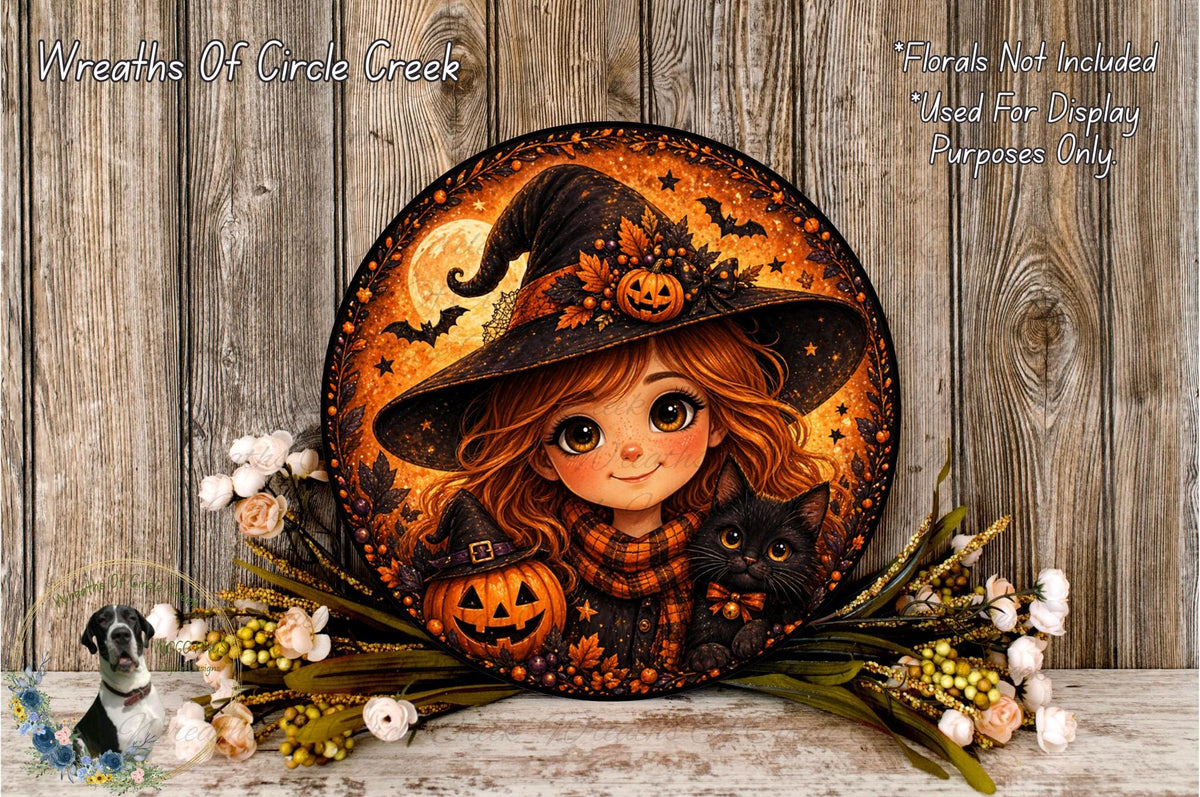 A round, decorative wreath featuring a young girl wearing a witch's hat and holding a pumpkin, surrounded by flowers and a black cat.