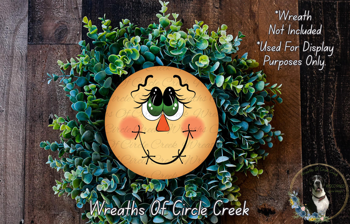 a wreath with a smiling face made of greenery, including small leaves and flowers. The wreath is displayed on a wooden surface, and there is a small dog in the bottom right corner of the image.