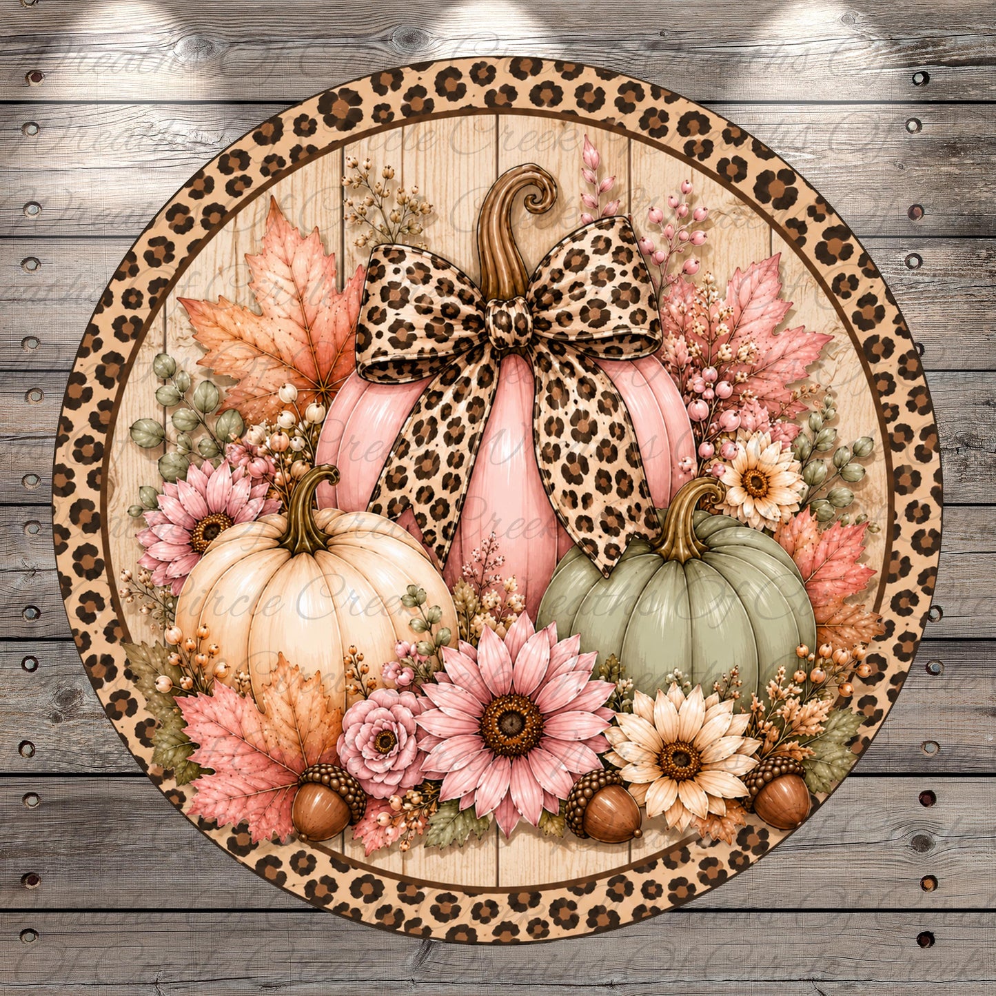 A round wreath with a leopard print border, featuring a pink pumpkin with a bow, surrounded by various fall-themed elements such as flowers, leaves, and acorns.