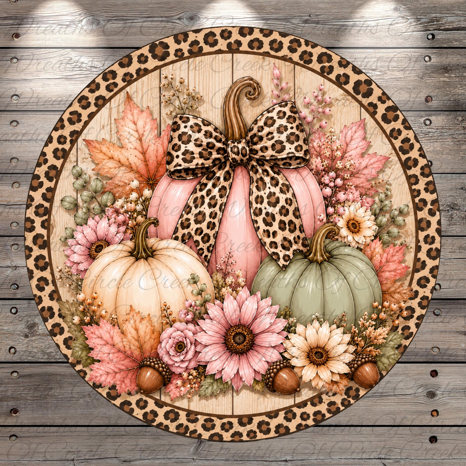 A round wreath with a leopard print border, featuring a pink pumpkin with a bow, surrounded by various fall-themed elements such as flowers, leaves, and acorns.