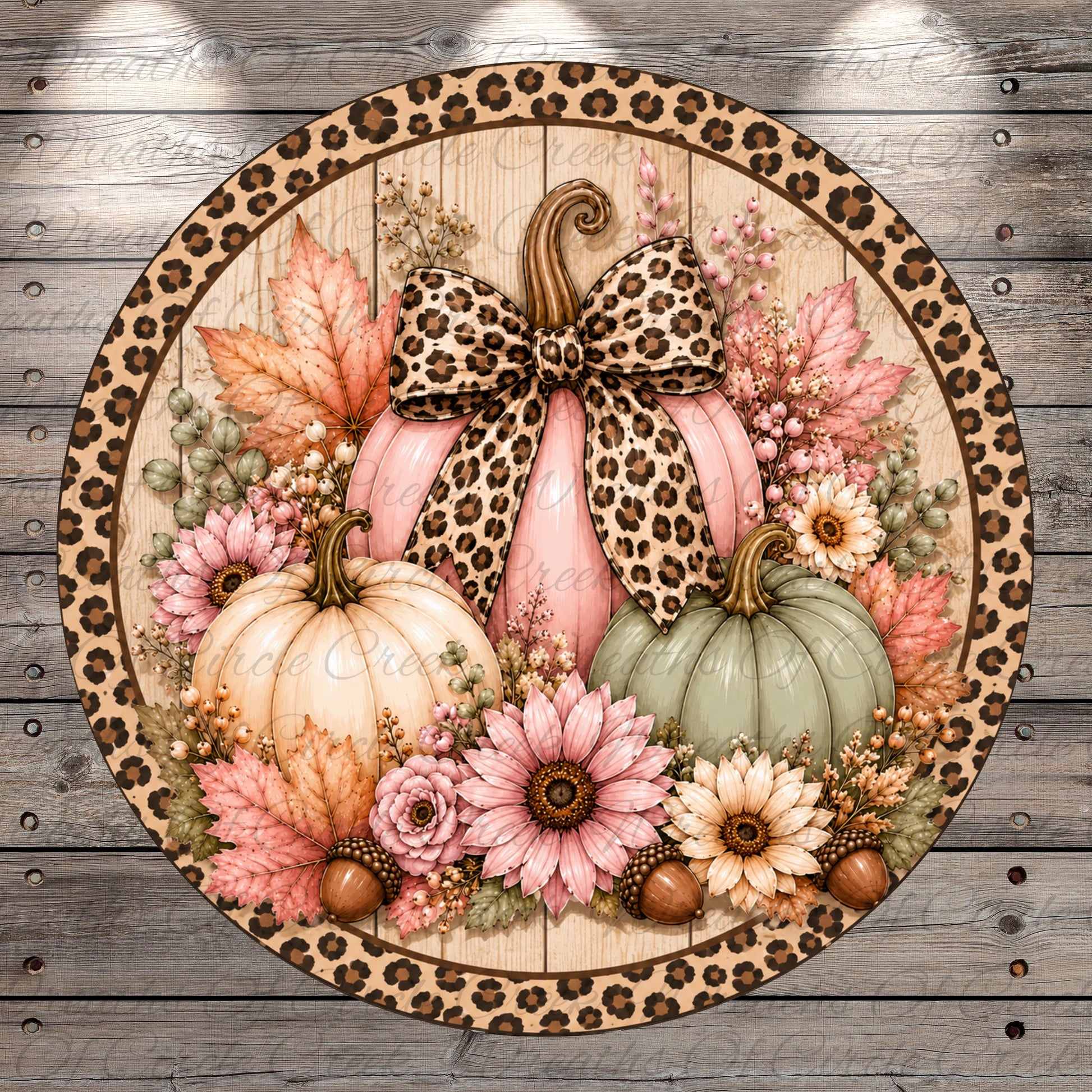 A round wreath with a leopard print border, featuring a pink pumpkin with a bow, surrounded by various fall-themed elements such as flowers, leaves, and acorns.
