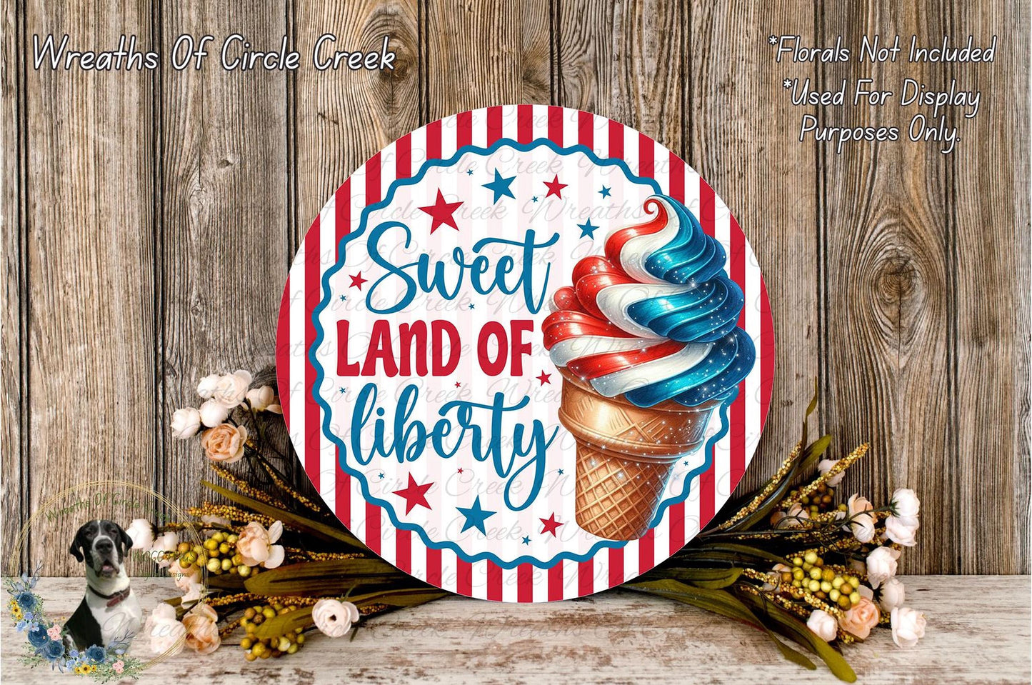 a round sign with a patriotic design, surrounded by flowers and a wooden background.