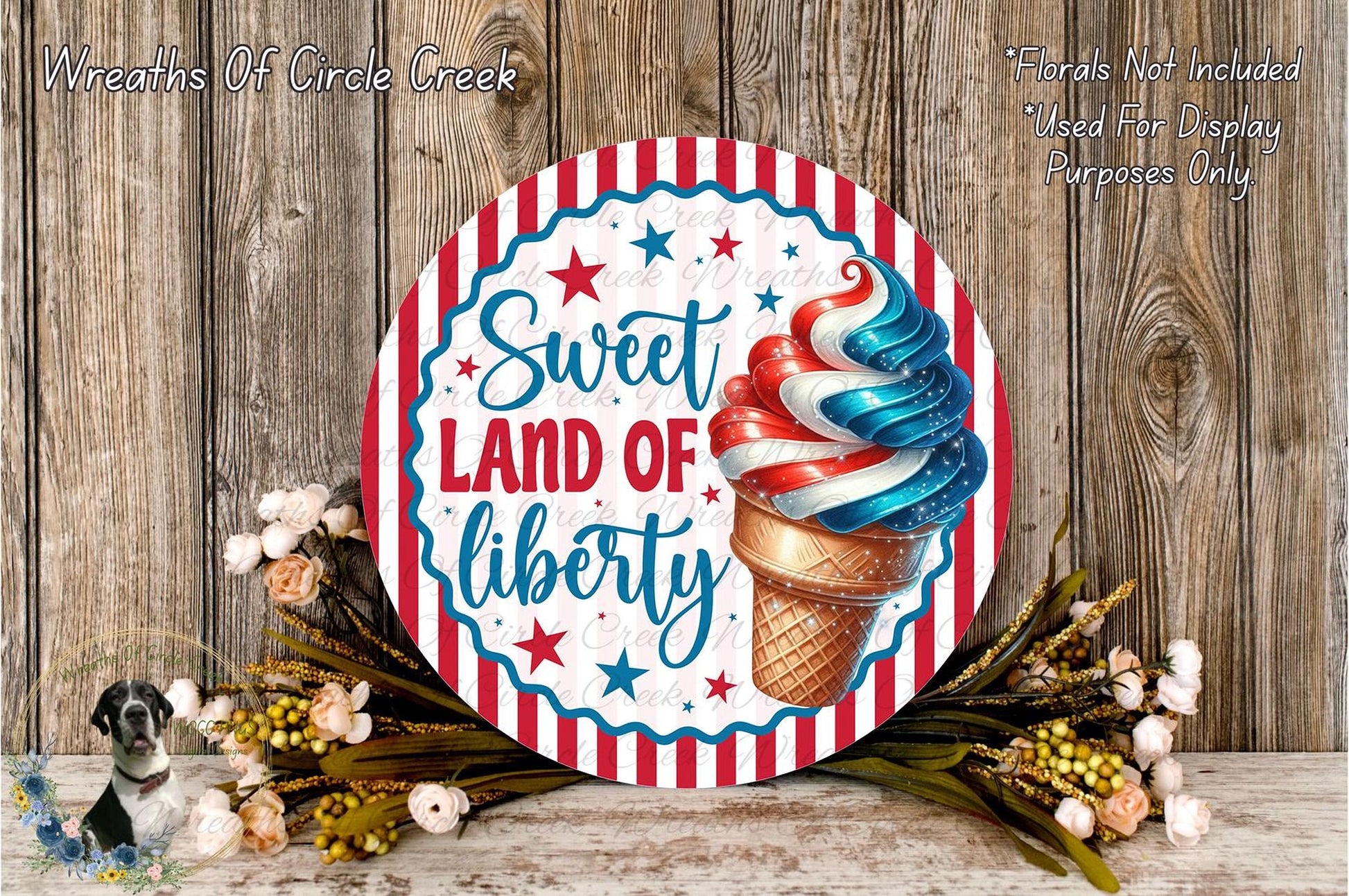 a round sign with a patriotic design, surrounded by flowers and a wooden background.