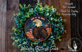 a wreath with an eagle and an American flag design, surrounded by greenery. The wreath is displayed on a wooden surface.
