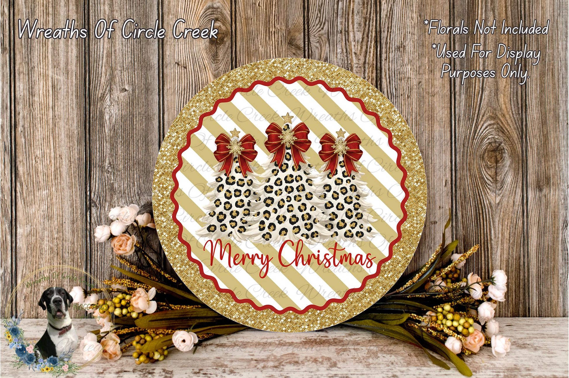 A festive Christmas wreath with a glittery gold border and a red ribbon design, surrounded by a floral arrangement and a wooden background.