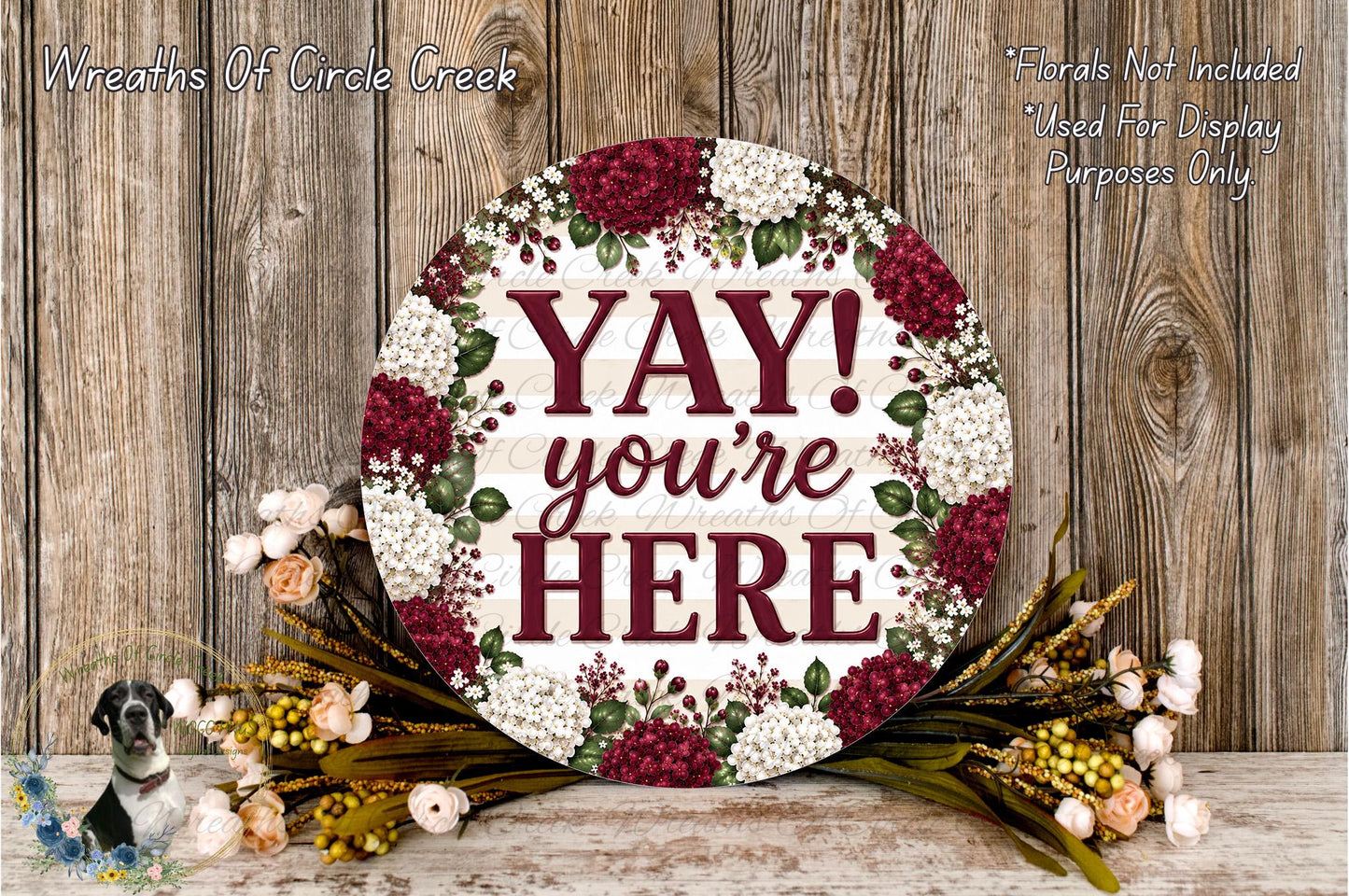 a round wooden sign with the text "YAY! you're here" surrounded by a floral arrangement.