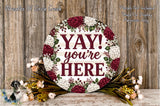 a round wooden sign with the text "YAY! you're here" surrounded by a floral arrangement.