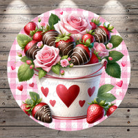 A bucket filled with chocolate-covered strawberries and roses, surrounded by hearts and leaves, set against a pink and white checkered background.
