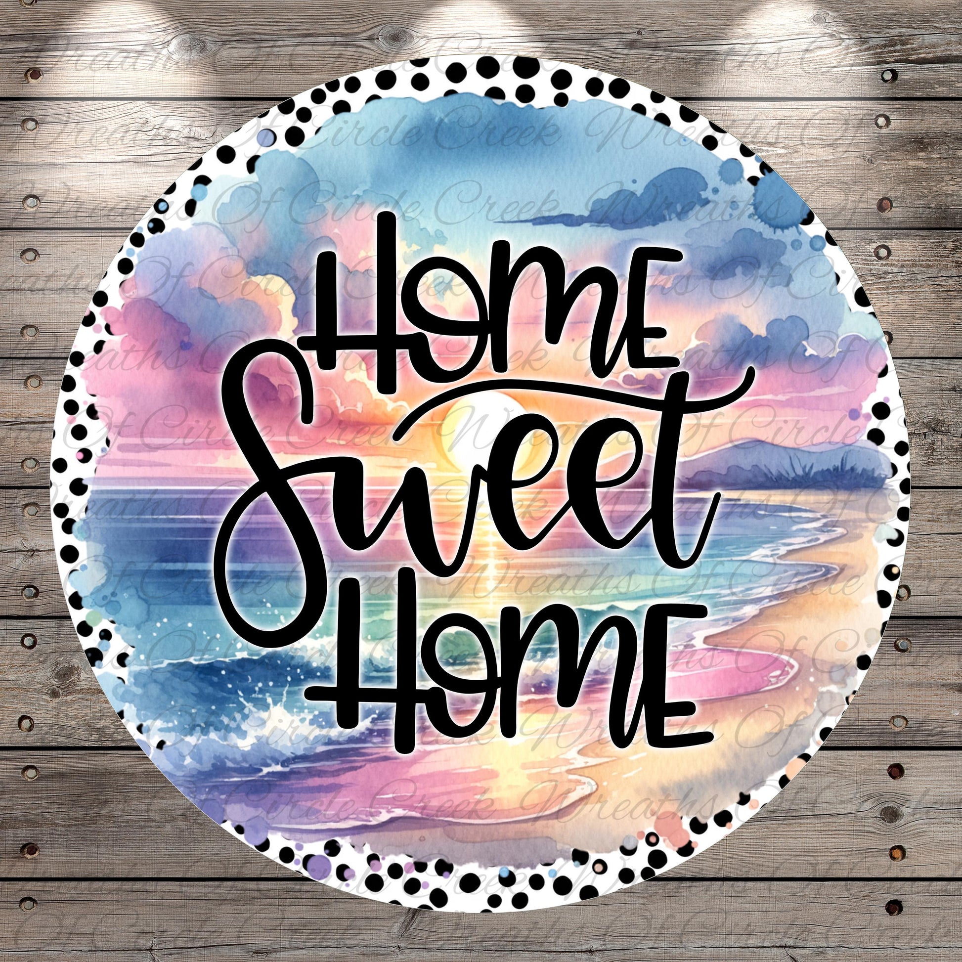 A circular design with a watercolor-style background depicting a sunset over a beach. The text "Home Sweet Home" is written in a cursive font in the center of the design.