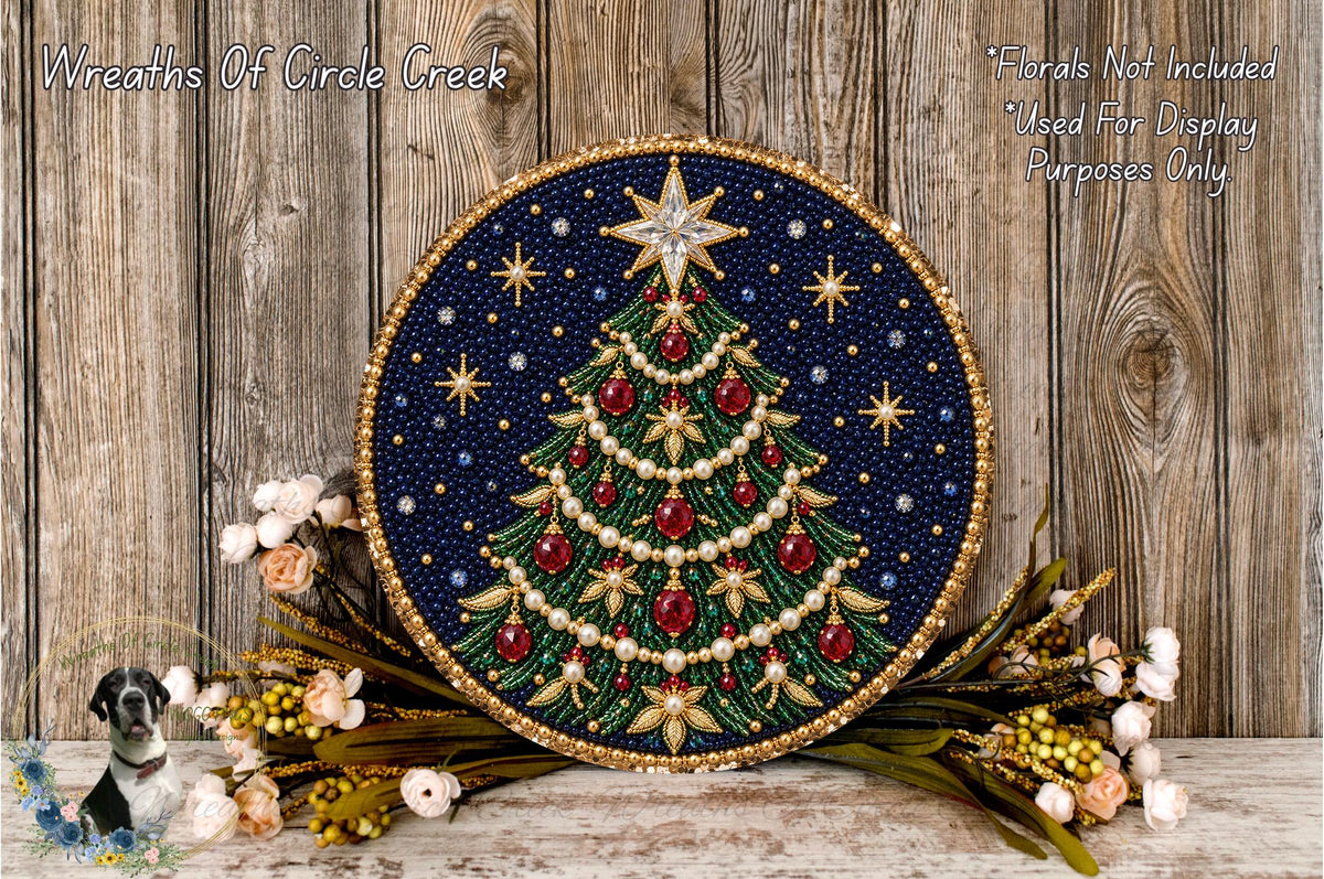 A circular, beaded Christmas tree wreath with a star at the top, surrounded by flowers and placed on a wooden surface.