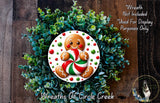 A wreath made of green plants and a gingerbread man figure, with the gingerbread man holding a candy cane.