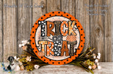 a Halloween-themed decoration with a large orange sign that says "TRICK TREAT" surrounded by a floral arrangement and a wooden background.