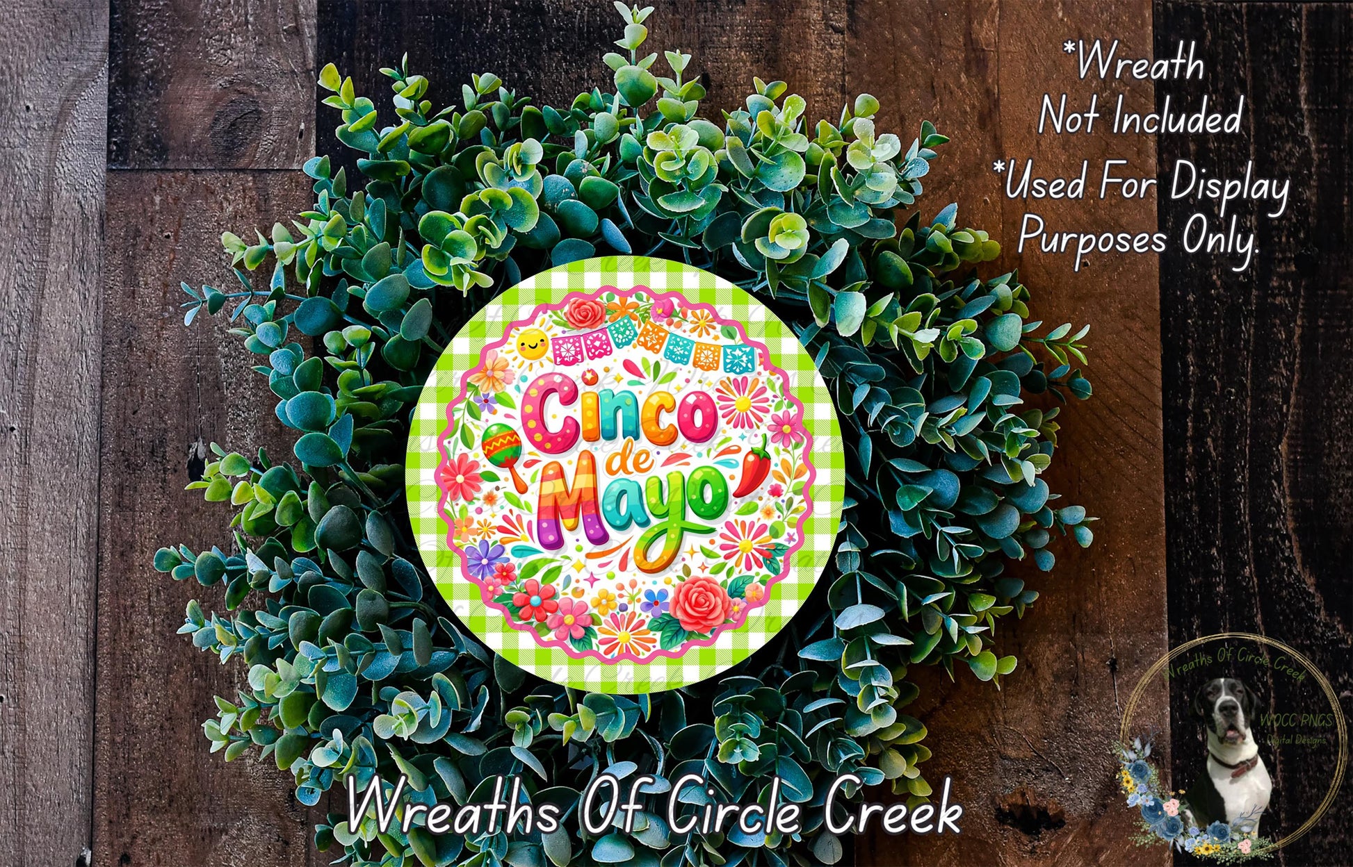 a wreath made of green leaves and flowers, with a colorful circular sign that reads "Cinco de Mayo" in the center.