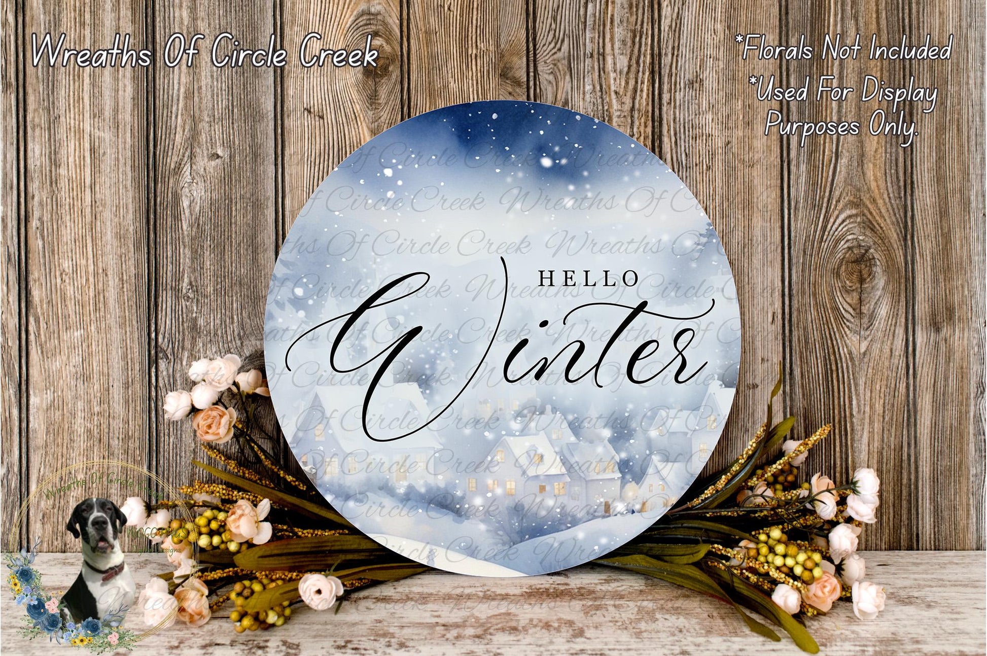 a round sign with the word "Hello Winter" written on it, surrounded by a wreath of flowers and a snowy landscape. The sign is placed on a wooden surface, and there is a small dog in the background.