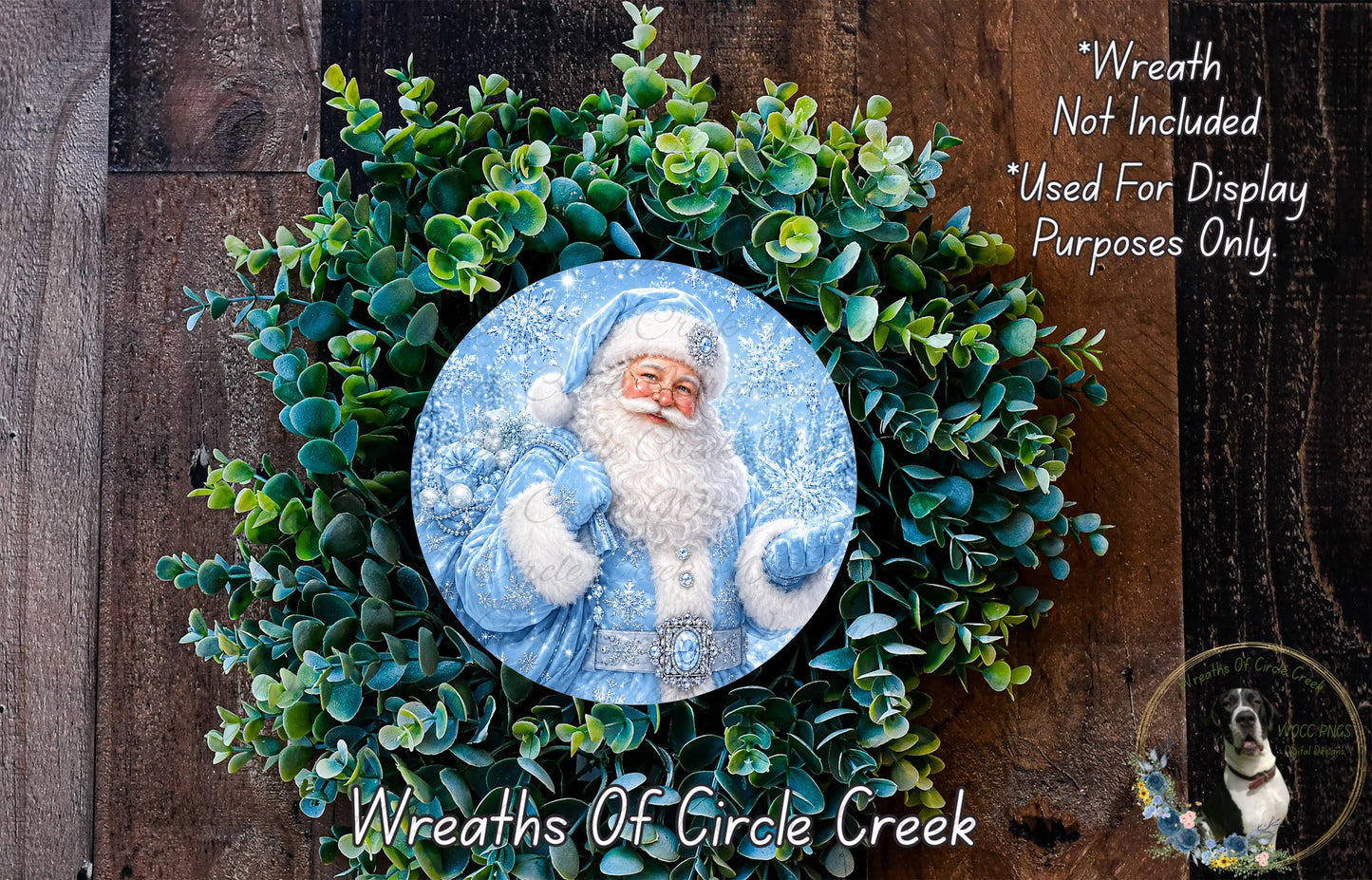 A wreath featuring a Santa Claus image, surrounded by a lush green wreath. The wreath is displayed on a wooden surface, and there is a text overlay that reads "Wreath Not Included * Used For Display Purposes Only".