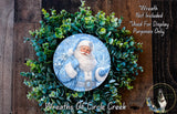 A wreath featuring a Santa Claus image, surrounded by a lush green wreath. The wreath is displayed on a wooden surface, and there is a text overlay that reads "Wreath Not Included * Used For Display Purposes Only".