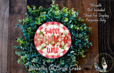 a wreath made of green leaves and flowers, with a red and white sign that says "Sweet Summer time" in the center.