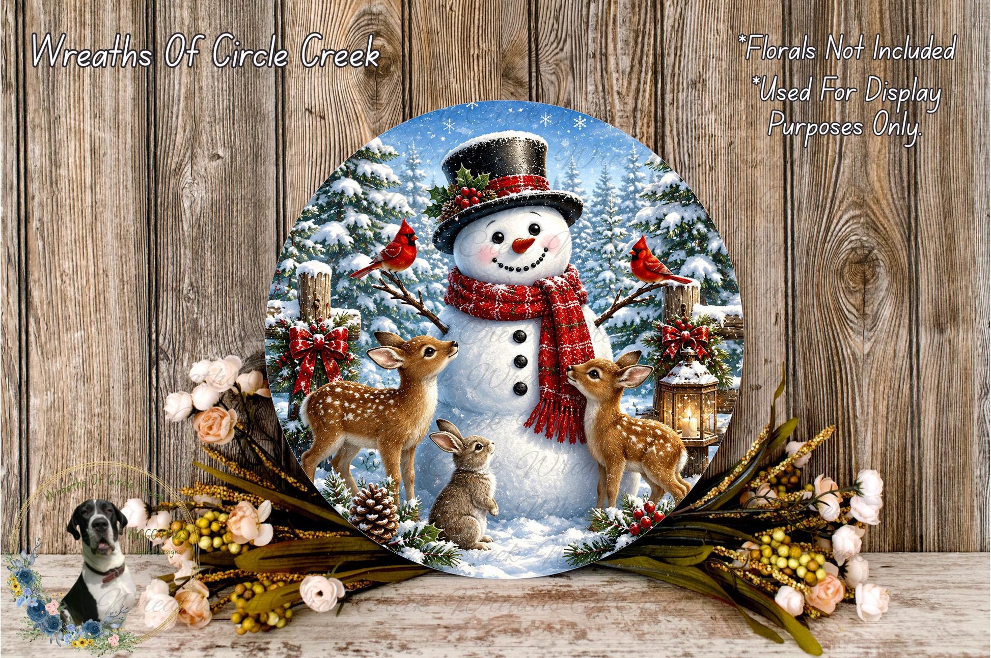 A snowman wearing a red scarf and top hat, surrounded by two deer and a rabbit, with a wreath of flowers and pine cones in the foreground.