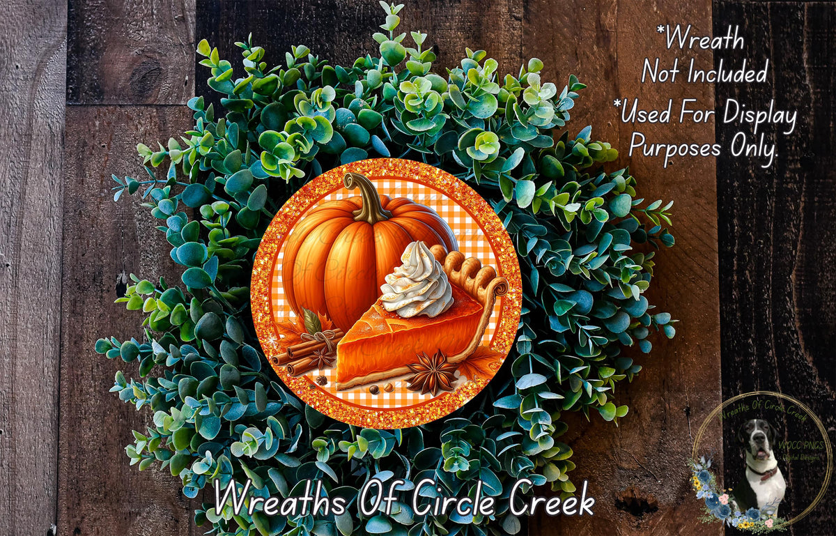 A wreath made of green foliage and a pumpkin with whipped cream on top, placed on a wooden surface.