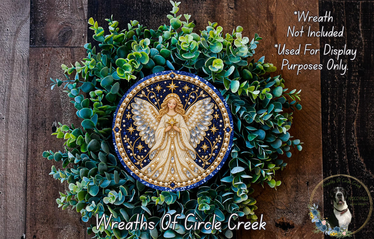 a wreath with a central design of an angel surrounded by green foliage. The wreath is displayed on a wooden surface, and there is a small dog in the bottom right corner of the image.