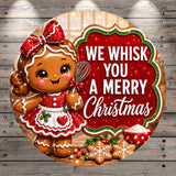 A cheerful gingerbread girl holding a whisk stands next to a sign that says "We whisk you a merry Christmas".