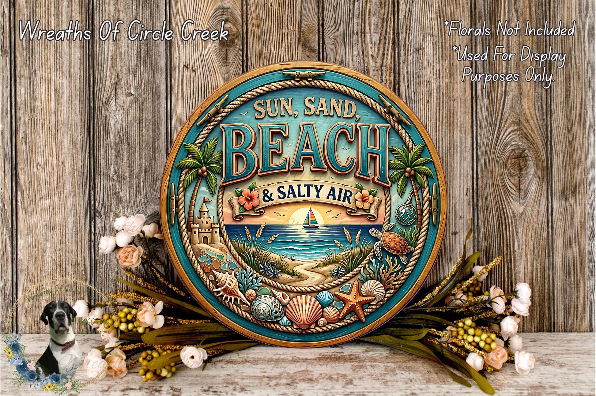 A decorative sign for "Sun, Sand, Beach & Salty Air" with a beach scene and various beach-related elements, such as palm trees, seashells, and a small boat. The sign is surrounded by a wreath of flowers and placed on a wooden surface.