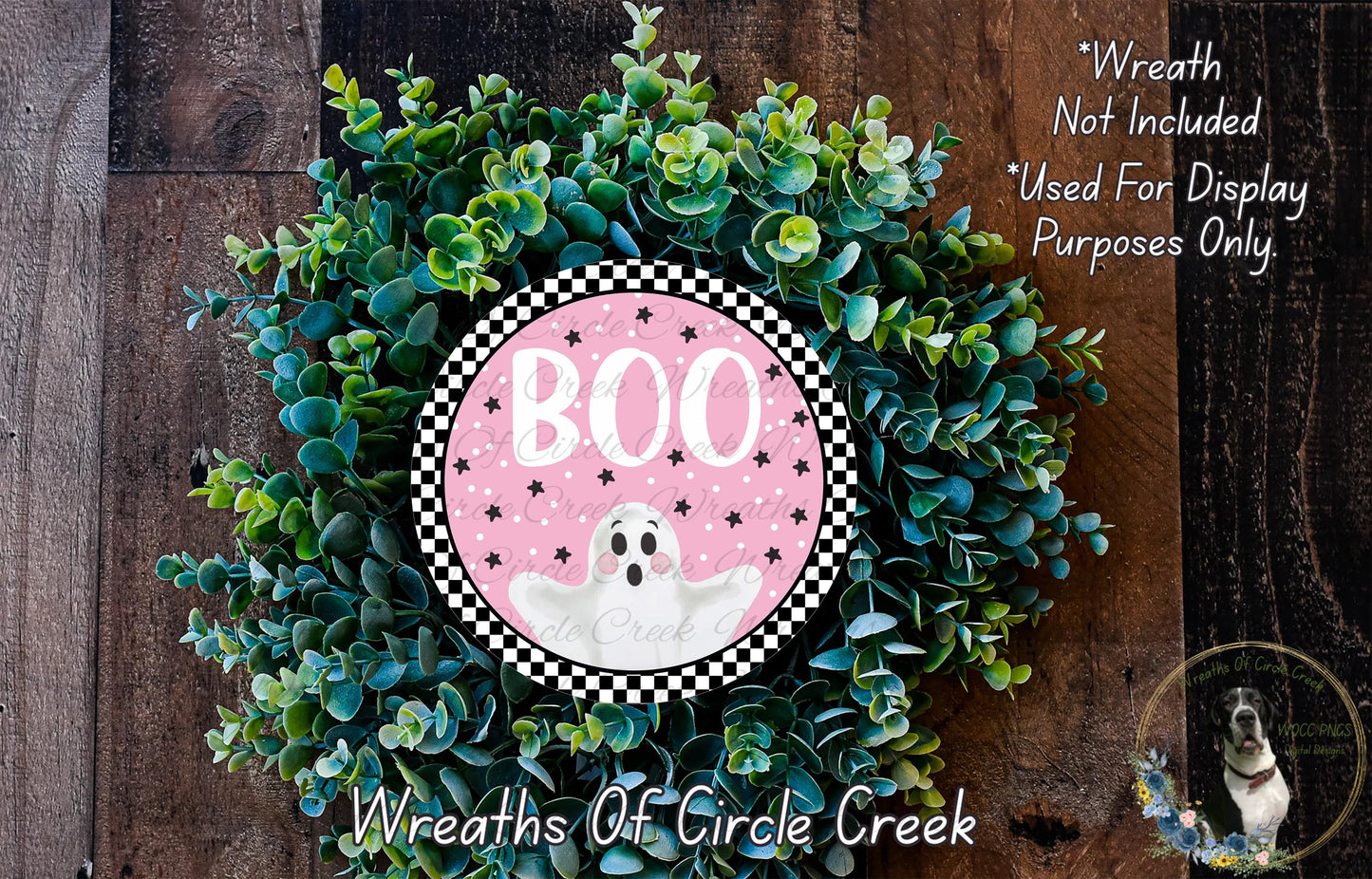 a Halloween-themed wreath made of green foliage and a pink circular sign with a ghost design.