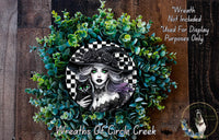 A wreath featuring a woman with a black cat, surrounded by green foliage. The wreath is described as a "Wreath of Circle Creek" and is not included in a display.