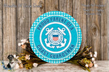 A round sign with the text "Proud Parent of a Coast Guard Guardian" displayed on it, surrounded by a bouquet of flowers and a wooden background.