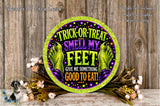 a Halloween-themed sign with a humorous message about trick-or-treating and smelling one's feet. The sign is surrounded by a floral arrangement and placed on a wooden surface.
