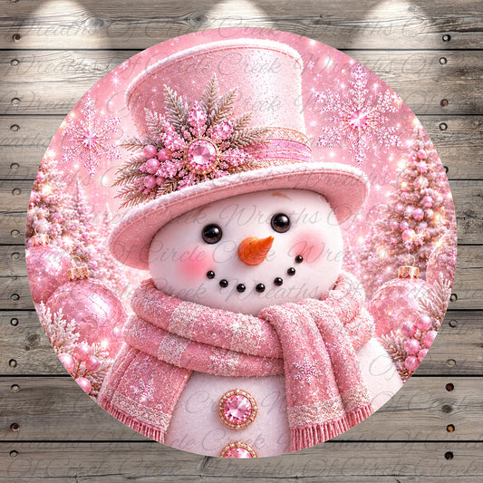 A pink snowman with a top hat and scarf, surrounded by pink and white Christmas decorations, is the central focus of the image.