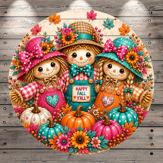 A round, decorative image featuring three colorful scarecrow dolls surrounded by pumpkins, flowers, and autumn leaves. The dolls are wearing hats and bow ties, and the overall scene has a cheerful and festive atmosphere.