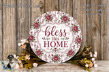 a decorative sign with the text "bless this home" surrounded by a floral arrangement and a wooden background.