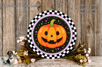 a Halloween-themed wreath with a jack-o-lantern design, placed on a wooden surface. The wreath is surrounded by a floral arrangement and has a checkered border.