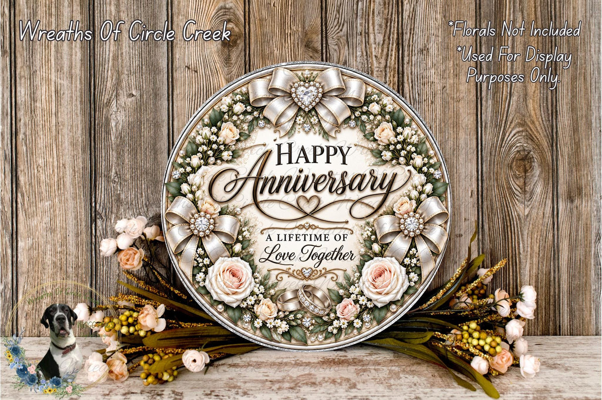 A decorative wreath with the text "Happy Anniversary" and "A Lifetime of Love Together" surrounded by flowers and greenery, placed on a wooden surface.
