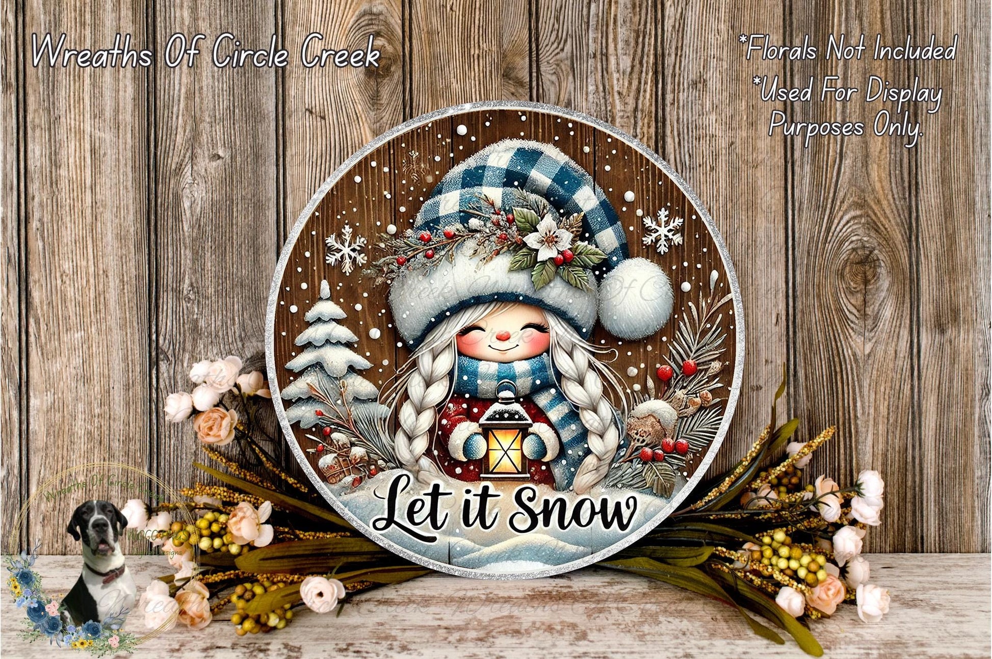 A decorative plate with a winter scene featuring a smiling girl, snowflakes, pine trees, and a lantern, surrounded by flowers and greenery.
