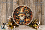 A gnome wearing a hat and holding a pumpkin is surrounded by autumn decorations, including flowers and leaves, on a wooden surface.