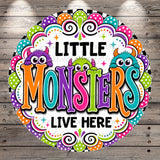 a colorful and whimsical design with the text "LITTLE MONSTERS LIVE HERE" surrounded by various monster-themed elements such as polka dots, stars, and swirls.